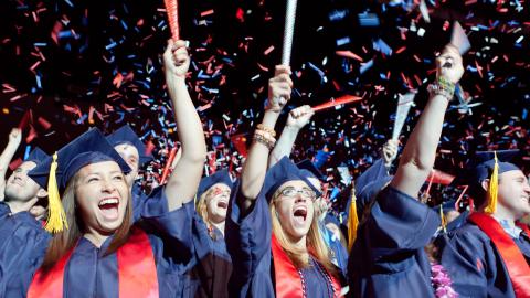 students cheering in graduation regalia 