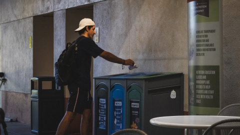 Person puts item into recycling bin.