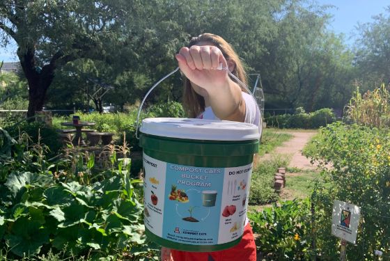 A student holding a compost bucket