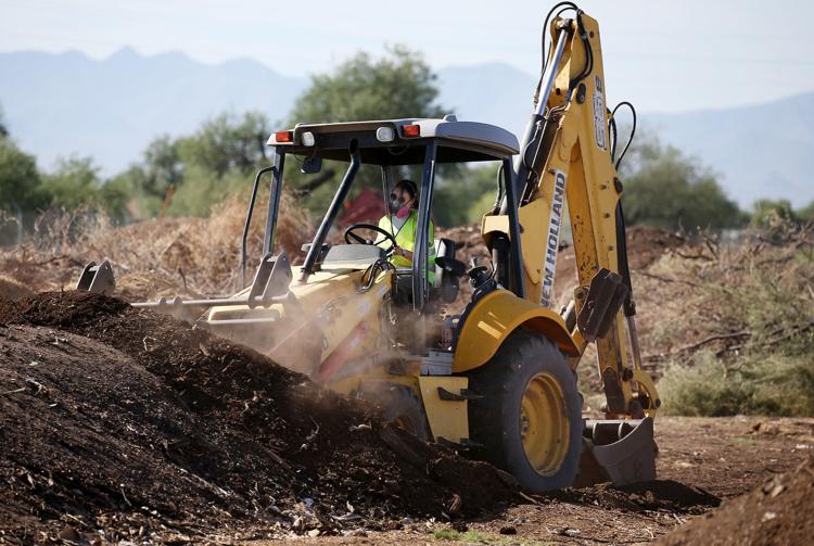 Madison Padgett operating a tractor behind a pile of compost.