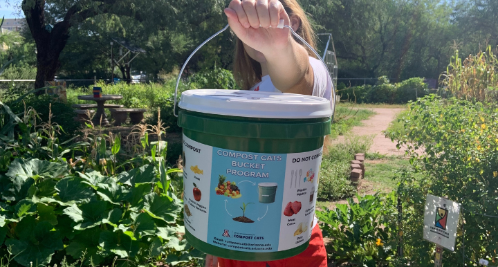 Student holding up a compost cats bucket