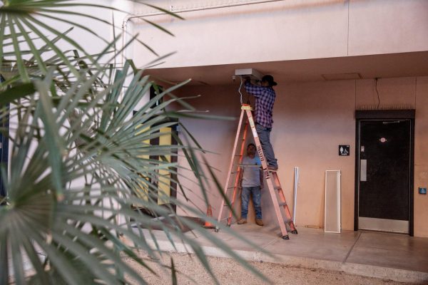 a man stands on a ladder to replace a ceiling lighting fixture