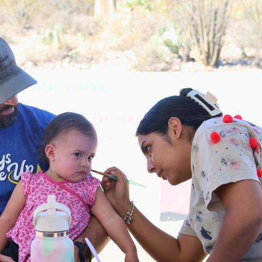 A person painting a little kid's face.