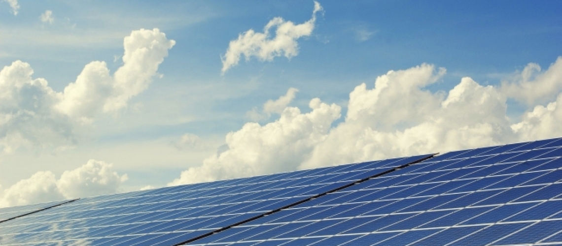 Solar panels against a partly cloudy blue sky. 