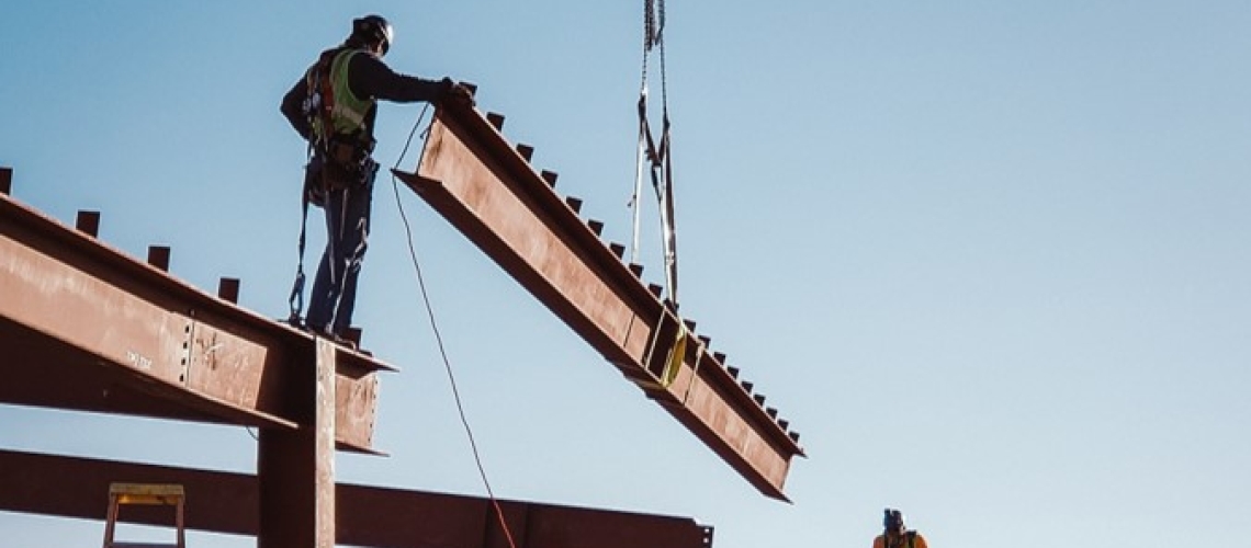 Construction workers lower a steel beam into place. 