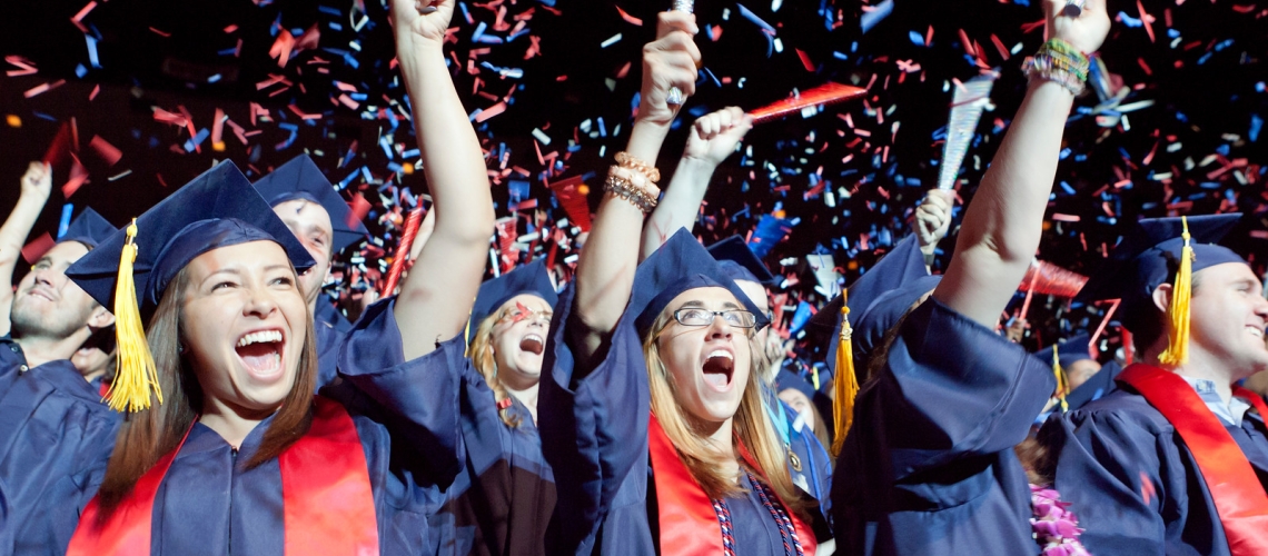 students cheering in graduation regalia 