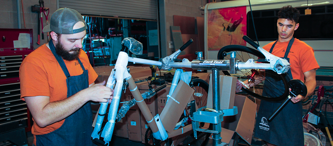 Two Outdoor Rec employees assemble a bike on a bike stand