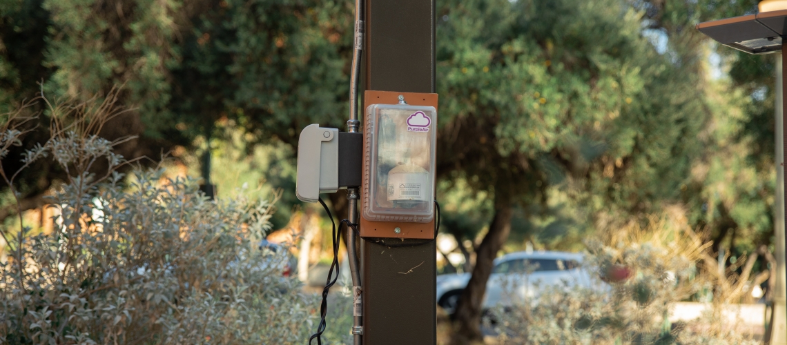 Air pollution sensor in the midst of a lush vegetated area of campus