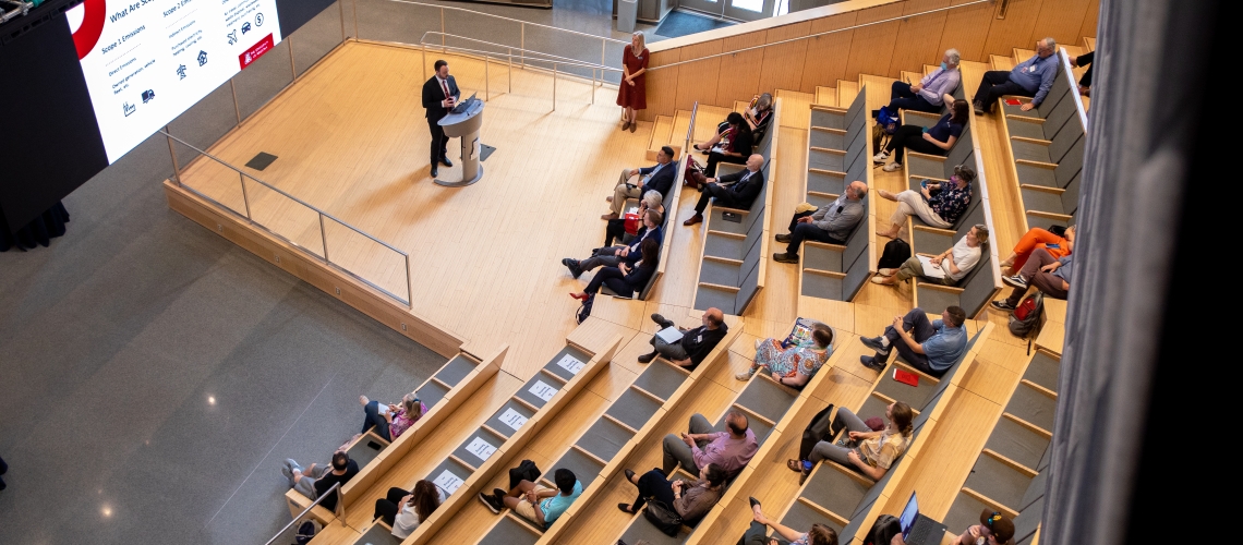 An audience listens to a speaker standing behind a podium.