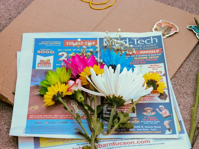 Various types of flowers laying on a newspaper that is on top of cardboard.