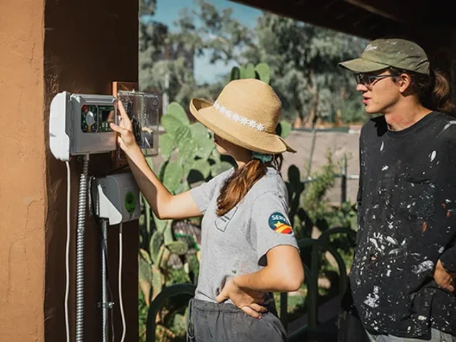 Two Office of Sustainability employees looking at an irrigation controller.