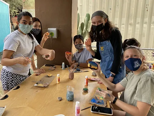 Students showing off their decorative river rocks they painted at a Garden event.