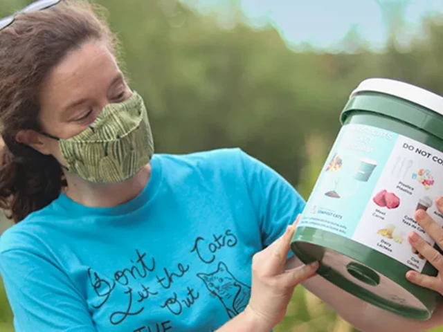 Woman reading the label of a Bucket Program compost bucket, wearing a cloth face mask.