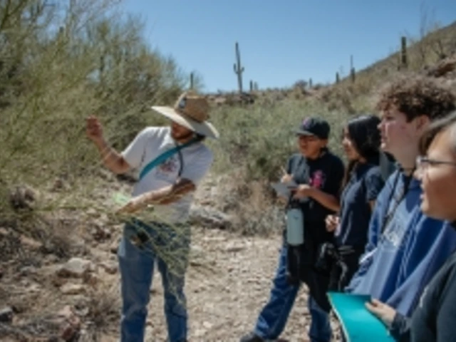 An educator is separating branches and explaining something to a group of students who are standing in a small wash.