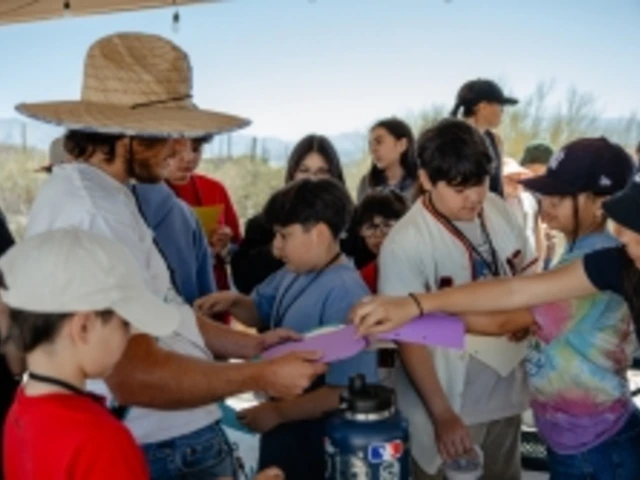 Children gather around an educator who is passing out supplies.
