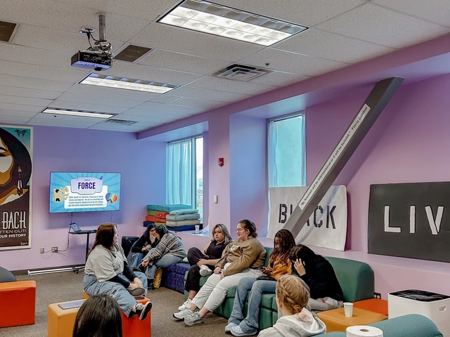 A group of people sitting together in a common area and talking to one another.