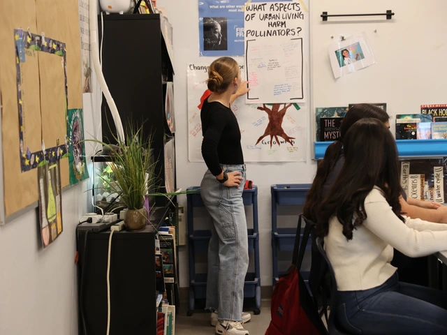 A person standing next to a paper taped on a whiteboard while talking to a group of students.