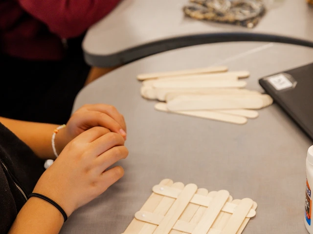 People glueing wooden popsicle sticks together in the shape of a square.