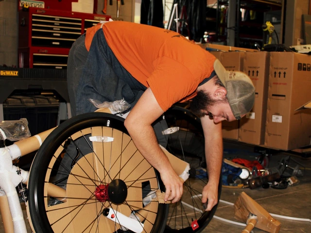 A person fixing a bike while leaning over a bike wheel.