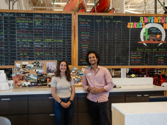 Two people standing next to each other, smiling, behind a desk.
