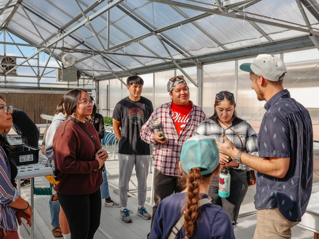 A group of people are standing together talking to one another inside of a greenhouse.