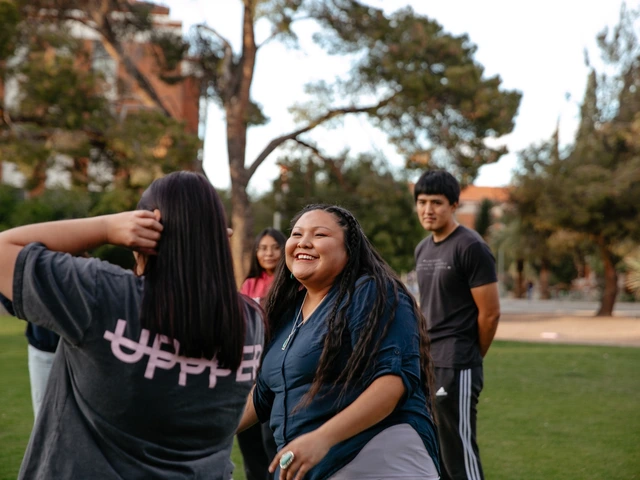 Three people standing next to each other talking. They are standing on a grass field.