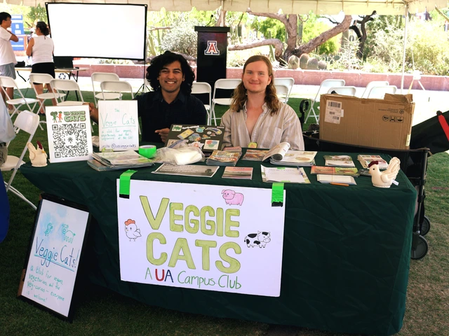 Two people smiling and sitting behind a table covered in outreach material.