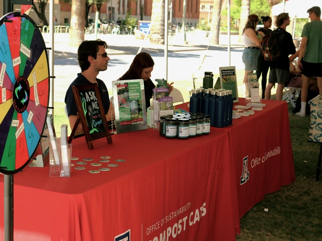 Two people sitting behind a table that is covered with outreach material and a red cloth.