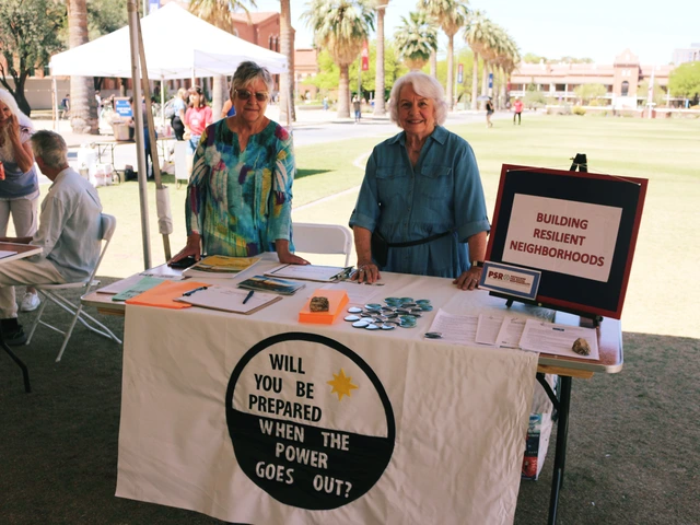 Two people smiling and standing behind a table covered in outreach material.