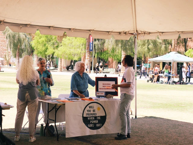 People standing next to a table covered in outreach material. They are talking to the people standing behind the table.