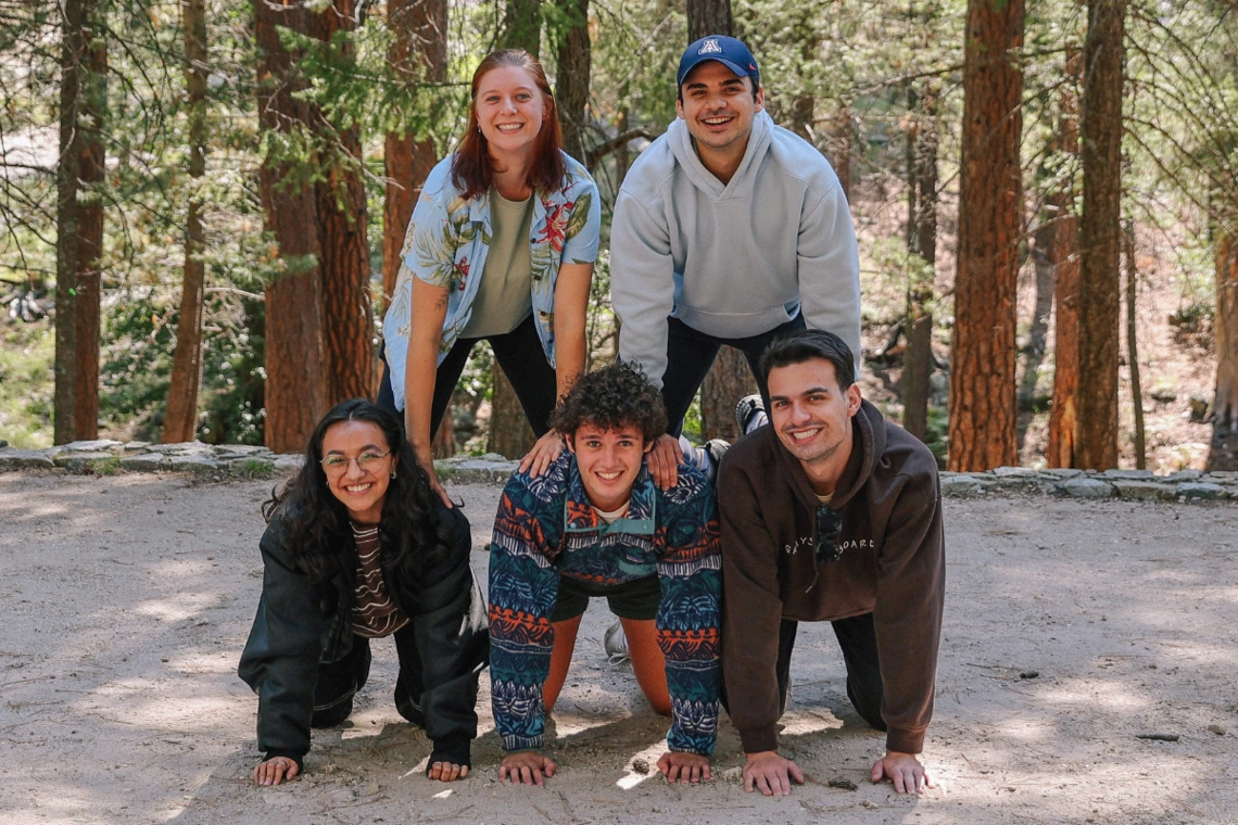 5 Students posing for the camera as a human pyramid