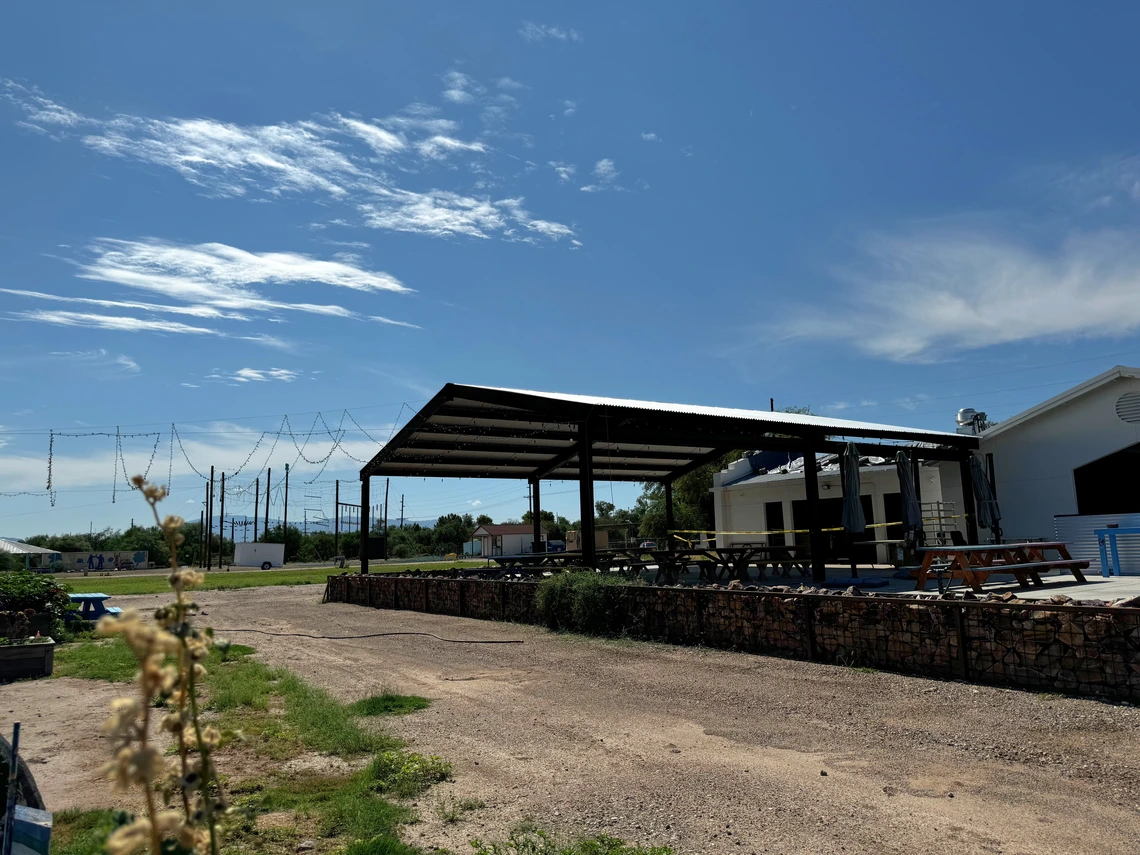A large shade structure covers outdoor picnic tables.