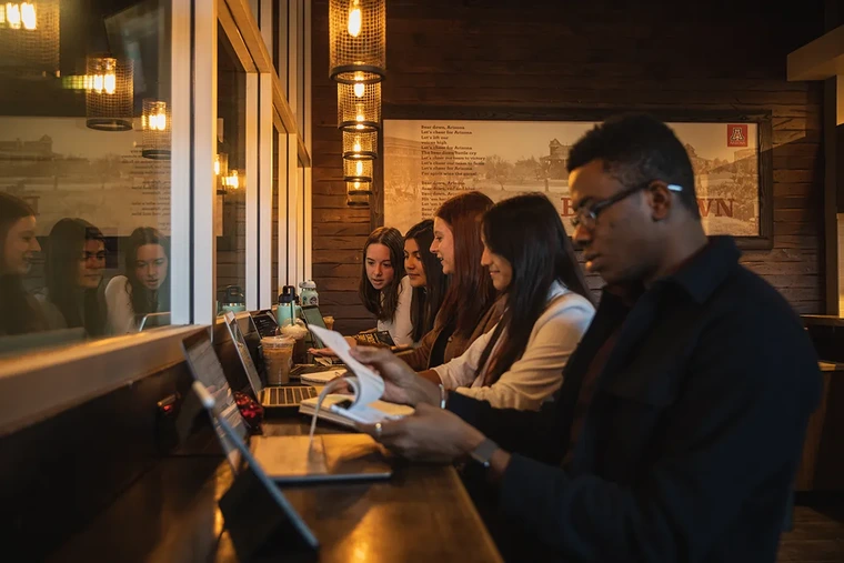 A row of five people working on laptops.