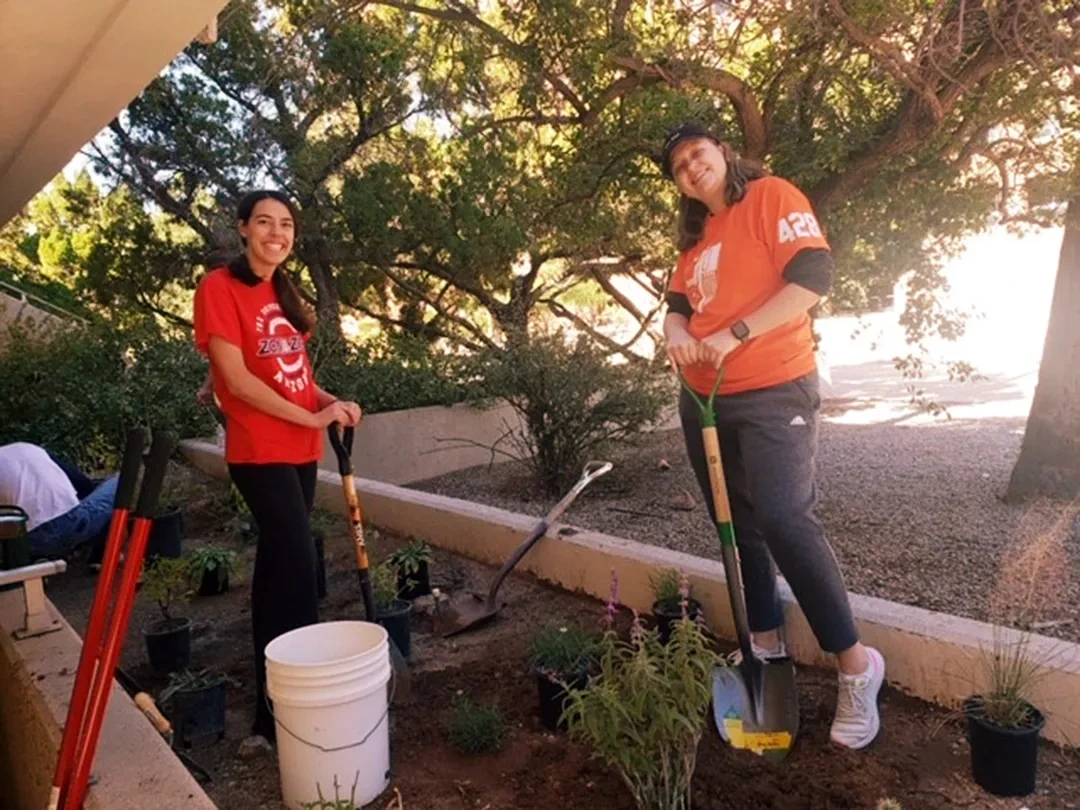2 people holding shovels getting ready to place native plants.