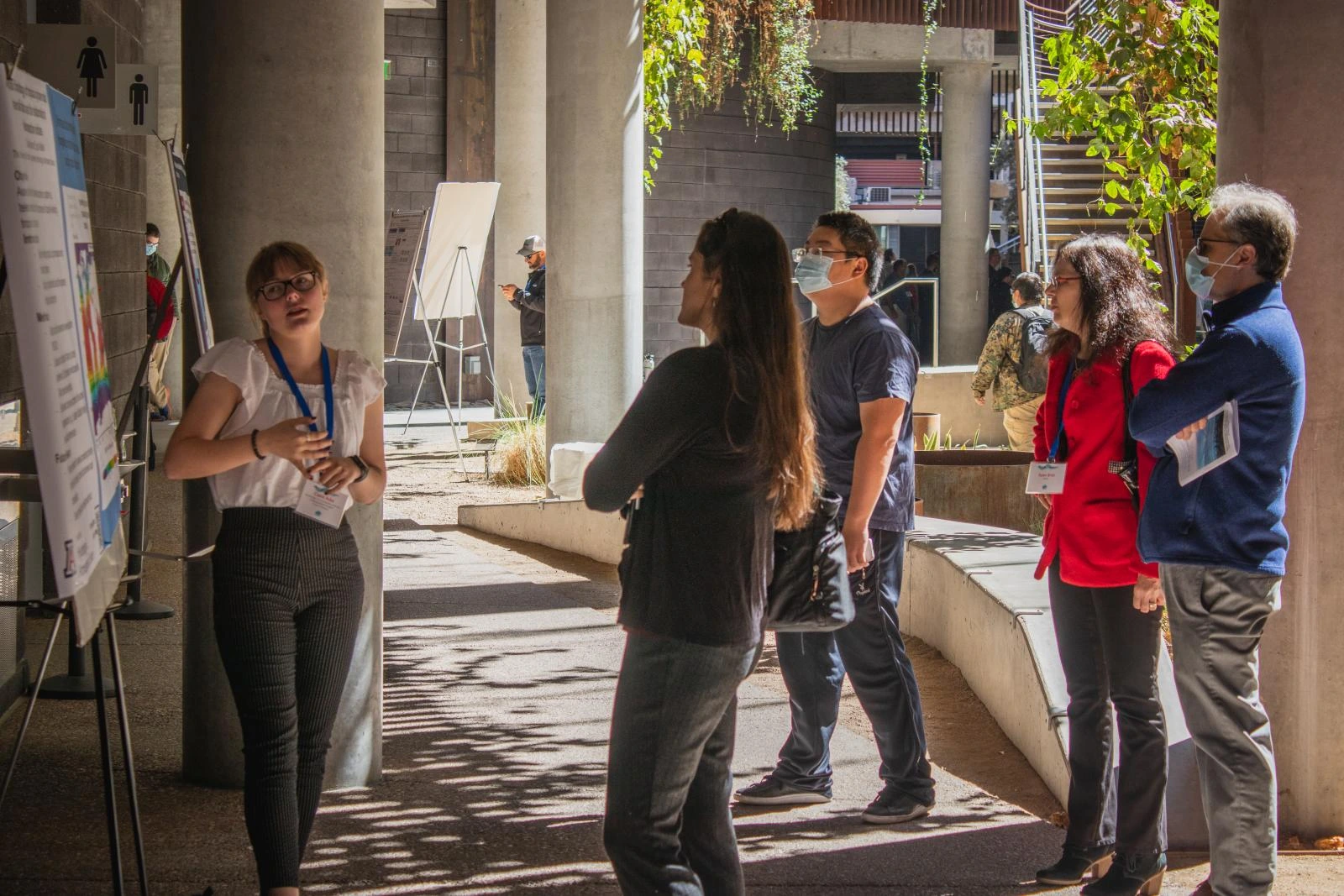 One individual presents their research poster to an audience of 4 individuals. 
