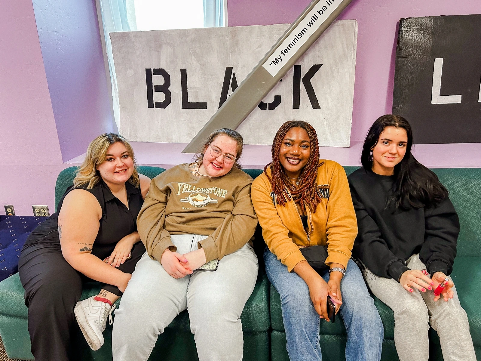 Four people sitting next to each other on a couch smiling.