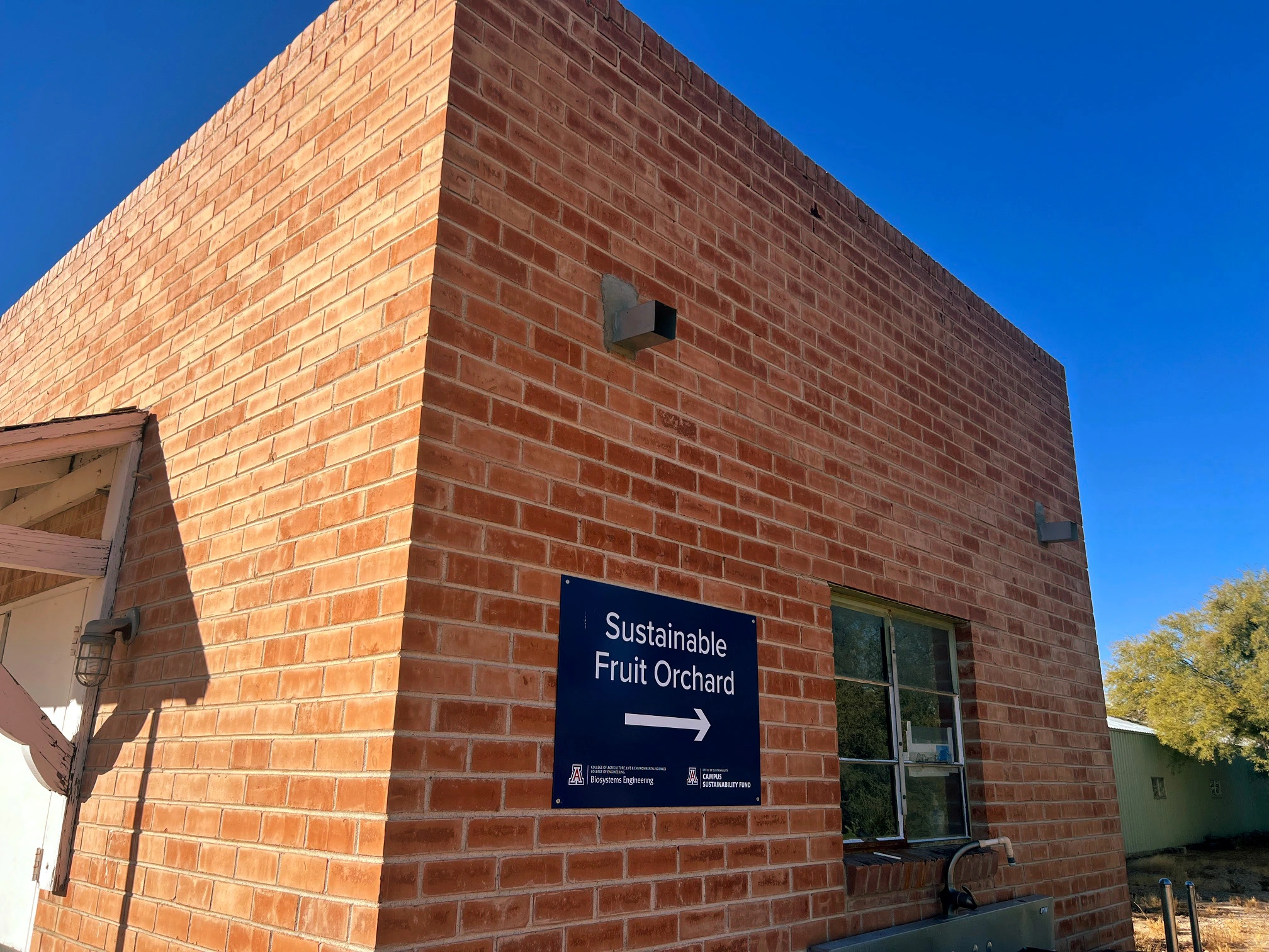 A red brick building with a blue sign on the wall.