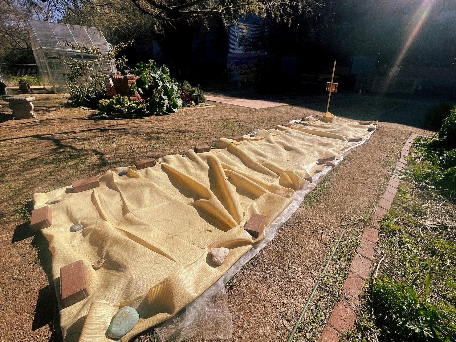 A garden plot that is covered with a sun protecting tarp.