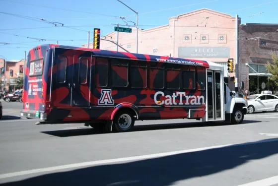 A large bus with the letters 'Cat Tran' on its side drives through an intersection.