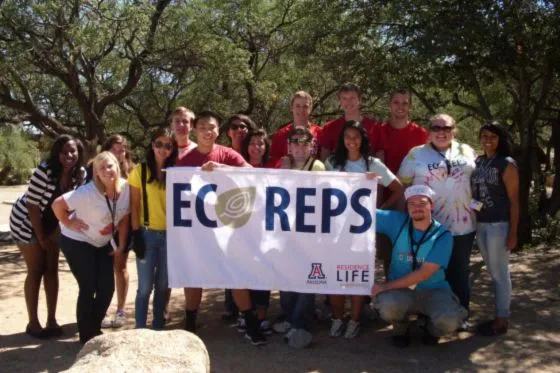 A group of students and their supervisor hold up a sign that reads ECOREPS.