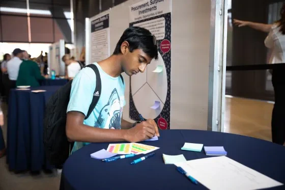 A student attending the Action Plan Kick Off Event fills out a survey.