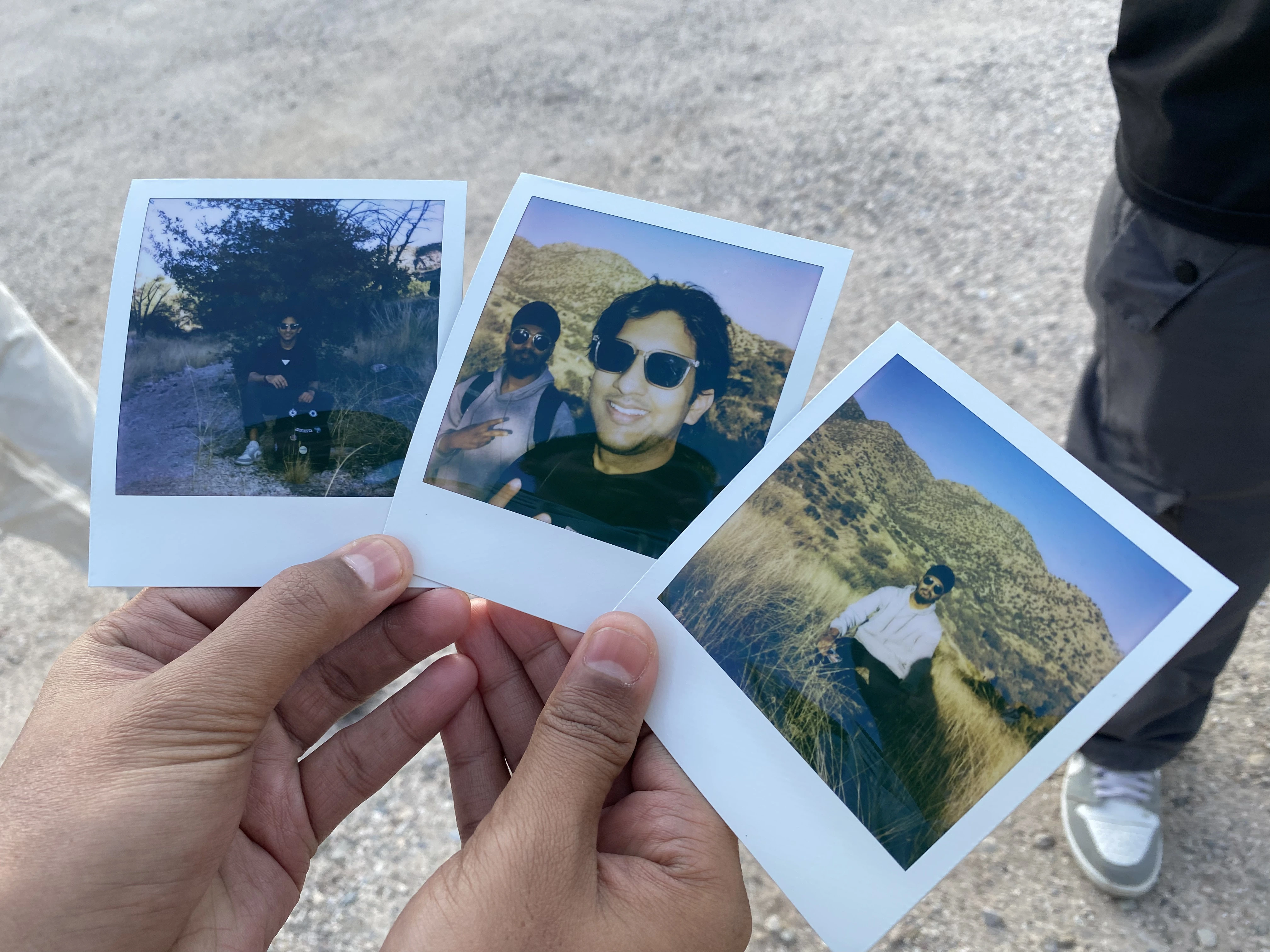 two hands are holding three polaroid images