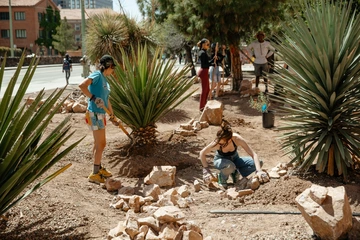 Two people creating a rain basin using large rocks