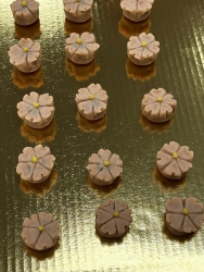 A golden tray with small red bean paste shaped as cherry blossoms.