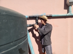 one person is inspecting the pipes that lead to a rainwater cistern