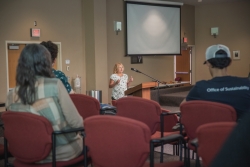 A person speaking behind a podium in front of a crowd of people.