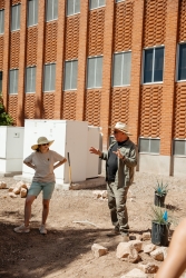 Two people standing in front of a building, talking to each other.