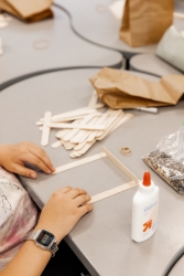 A person glueing wooden popsicle sticks together in the shape of a square.