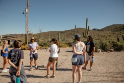 A group of people standing outside in a desert area.