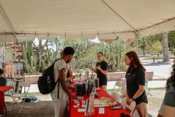 A group of people talking to two other people who are behind a red table.